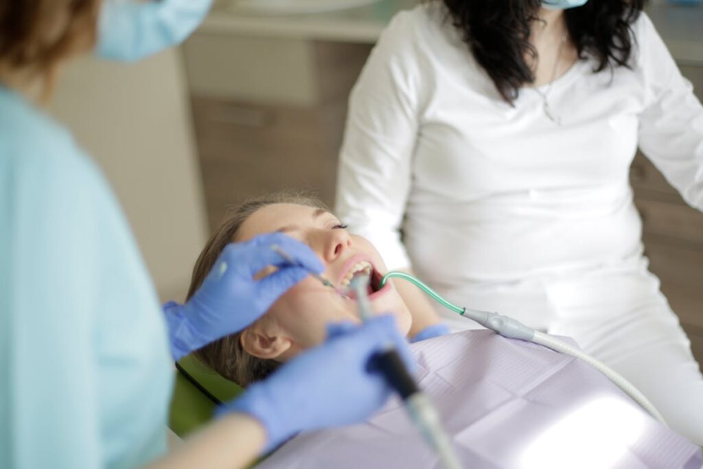 Crop dentist in gloves treating teeth of patient