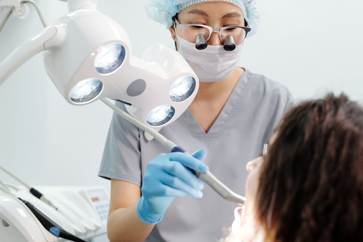 Woman in Gray Scrub Suit Holding Dental Equipment Woman in Gray Scrub Suit Holding Dental Equipment