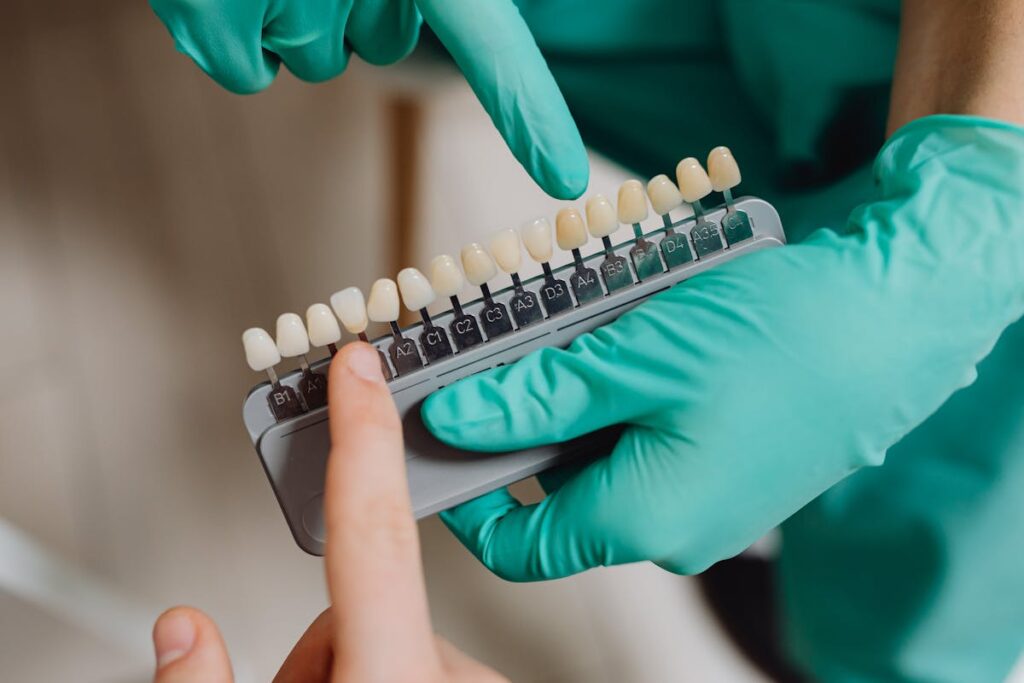 Dental professional with gloves pointing to a dental shade guide in a clinic.