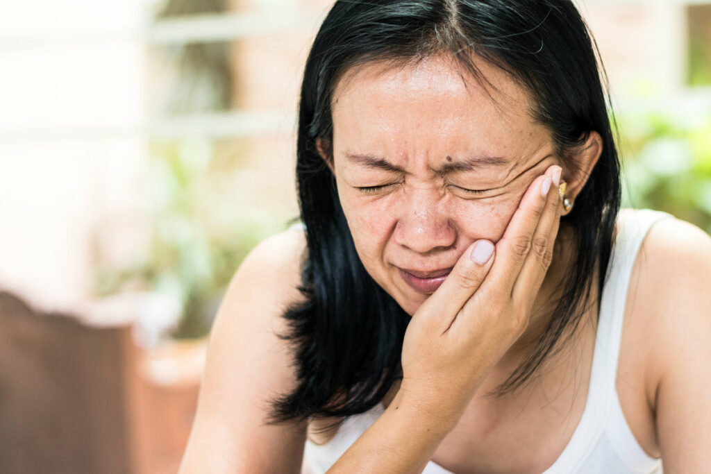 Temporomandibular Joint and Muscle Disorder: TMD concept. Woman hand on cheek face as suffering from facial pain or toothache