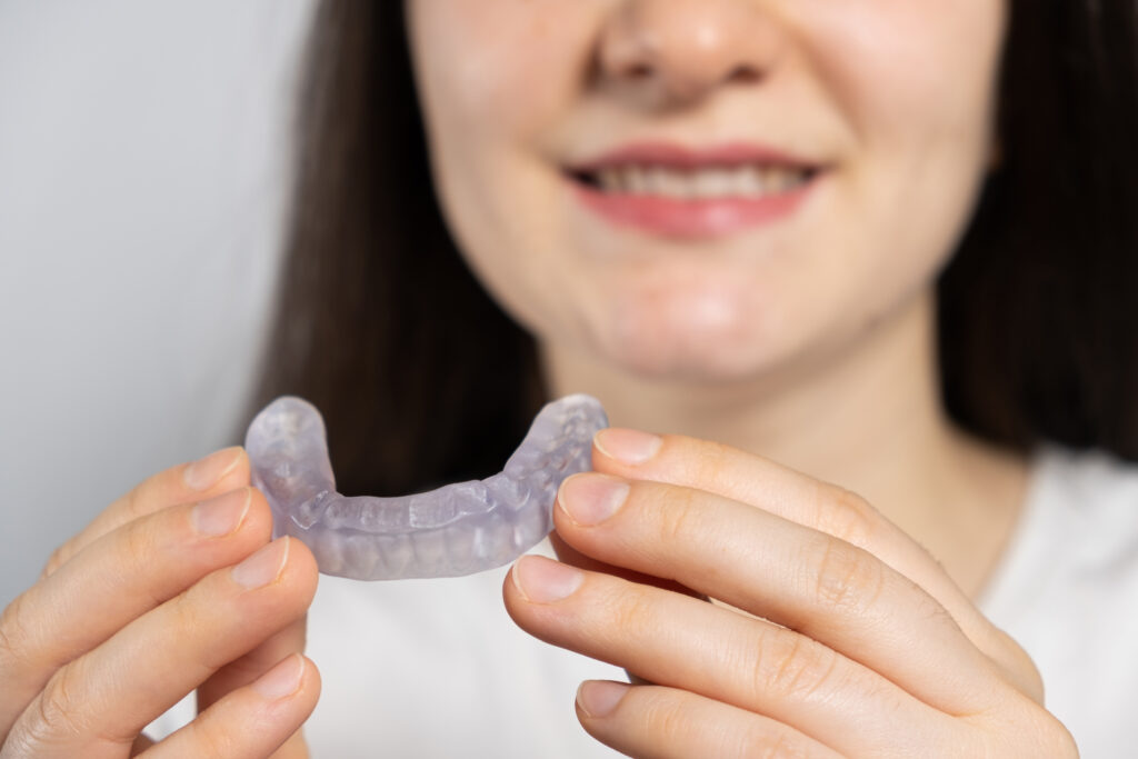 A woman holds dental mouthguard, splint for the treatment of dysfunction of the temporomandibular joints, bruxism, malocclusion, to relax the muscles of the jaw