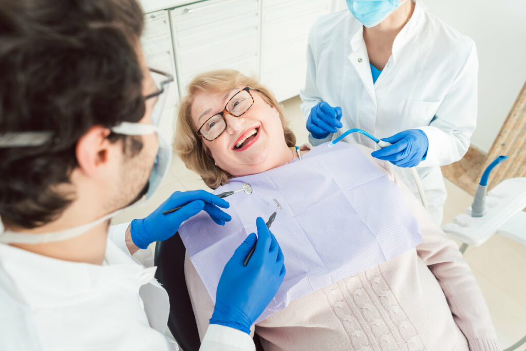 Team of dentists talking to senior patient in their surgery explaining the treatment