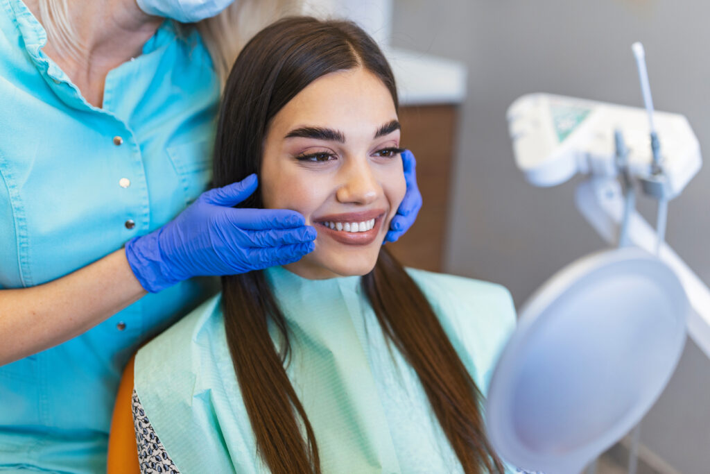Woman looks in the mirror in dentist chair.Viewed oral hygiene. Woman at the dentist. Woman in the dental chair dental treatment during surgery.